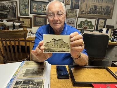 Merle Vastine, of Davenport, holds a postcard showing the last location of the Davenport Pearl Button Co. at the southeast corner of 5th and Taylor streets, Davenport.